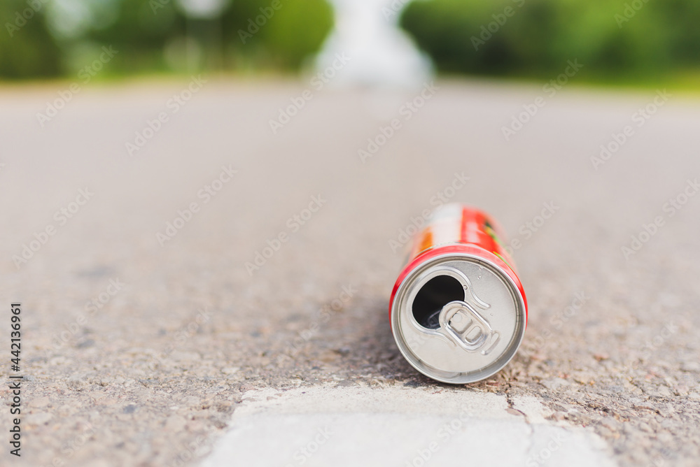 Aluminum can is flat lay,lying on a road. can fall on the street, It can be recycled.Summer day blurred background. Aluminum can is flat lay,lying on a road. can fall on the street, It can be recycled.Summer day blurred background.