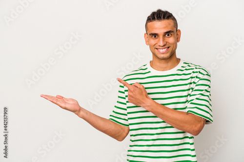 Young venezuelan man isolated on white background excited holding a copy space on palm.