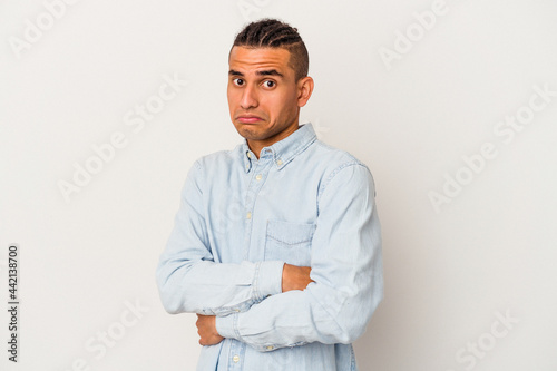 Young venezuelan man isolated on white background tired of a repetitive task. © Asier