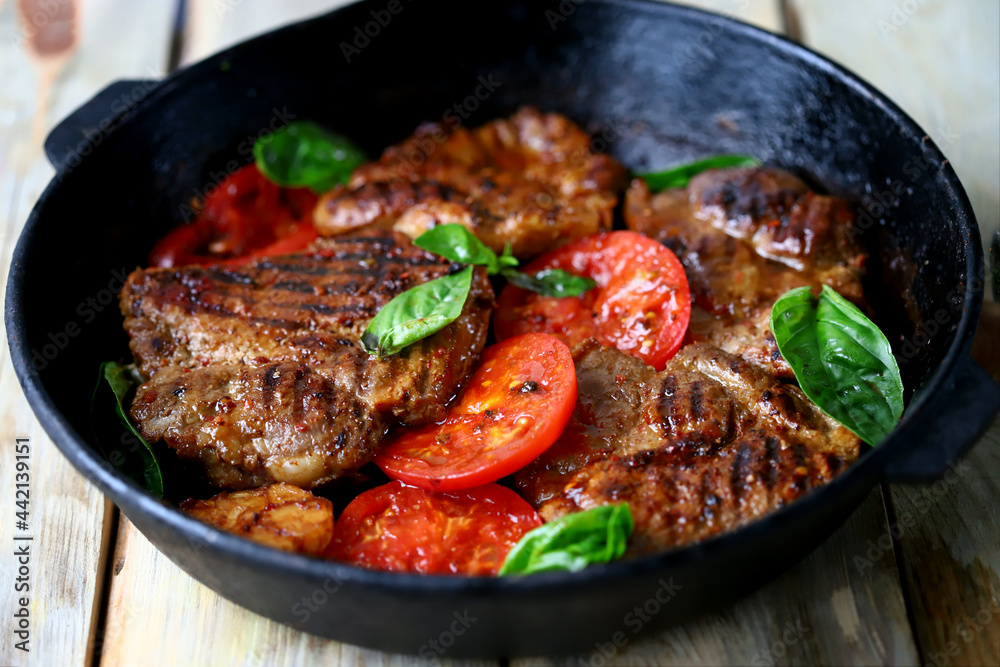 Fototapeta premium Appetizing juicy grilled steak with grilled vegetables in a pan. Close-up.