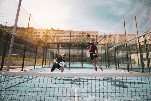 two paddle tennis athletes playing a match on an outdoor court