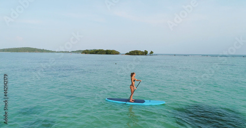 Aerial drone bird's eye view of man exercising sup paddle board in turquoise tropical clear waters, Thailand