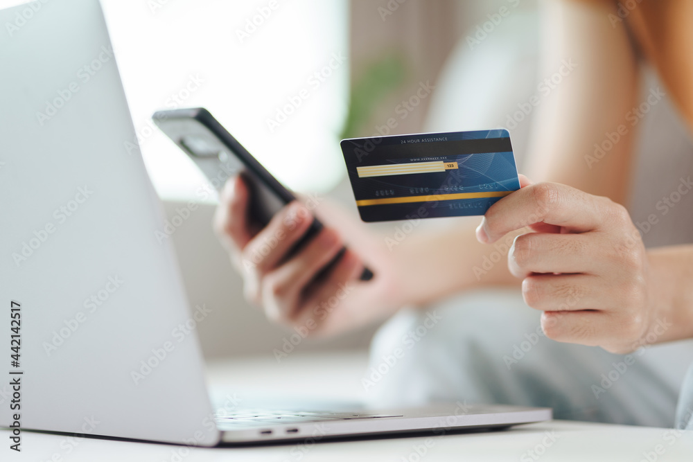 Young woman holding credit card and using smart phone for online shopping, internet banking, e-commerce, spending money, working from home concept Young woman holding credit card and using smart phone for online shopping, internet banking, e-commerce, spending money, working from home concept