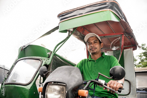 A middle aged Filipino tricycle driver in a green tricycle. photo