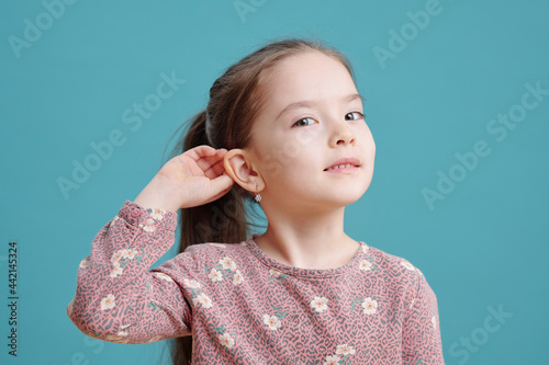 Photo Cute little girl showing new earrings on ear