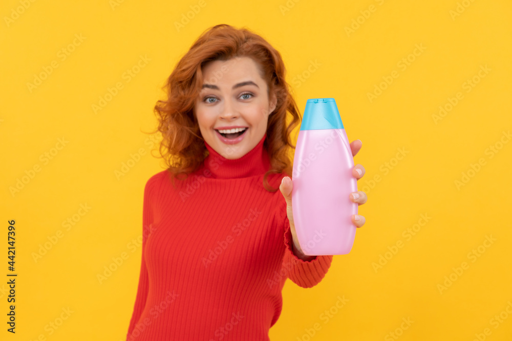 happy redhead woman curly dyed hair presenting body care product of shampoo, beauty happy redhead woman curly dyed hair presenting body care product of shampoo, beauty
