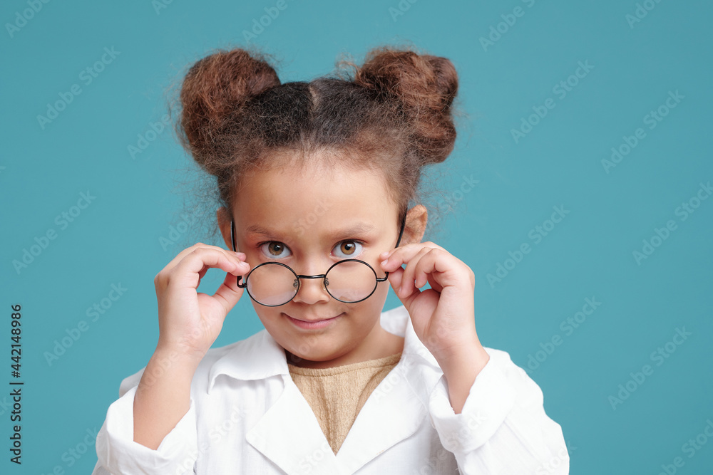 Serious little girl in whitecoat looking at you over eyeglasses Serious little girl in whitecoat looking at you over eyeglasses
