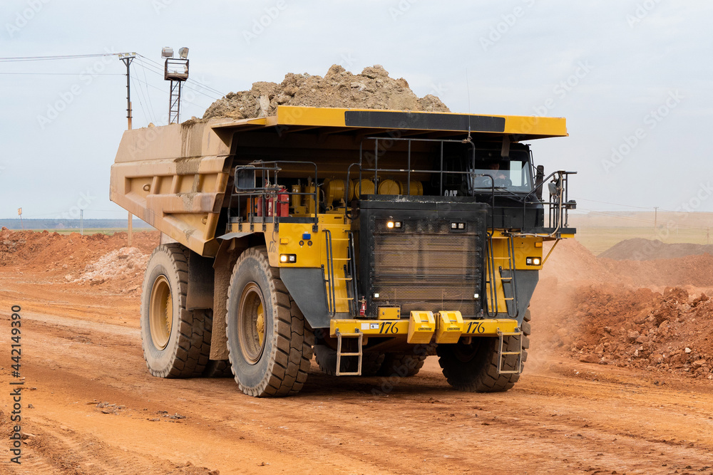 a mining dump truck drives and unloads bauxite minerals