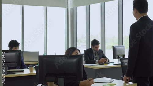 middle age asian manager say hi to colleagues in office in morning