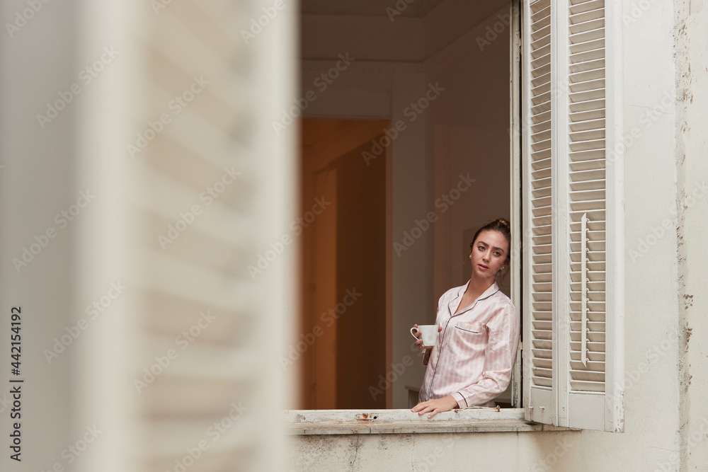 Woman drinking beverage near window Woman drinking beverage near window
