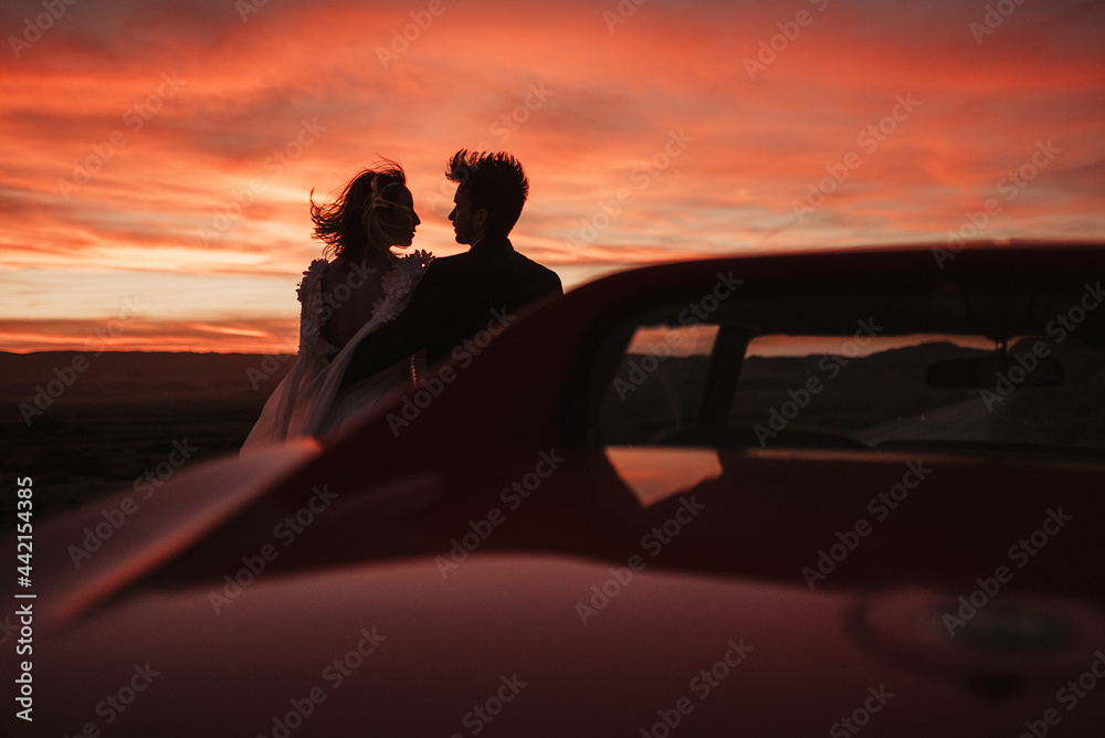 Loving couple resting near car at sunset Loving couple resting near car at sunset