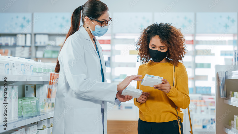 Fototapeta premium Covid-19 Pharmacy Wearing Face Masks: Professional Pharmacist Helping Beautiful Female Customer with Medicine Recommendation, Talking. Drugstore with Full of Drugs, Pills, Health Care, Beauty Products