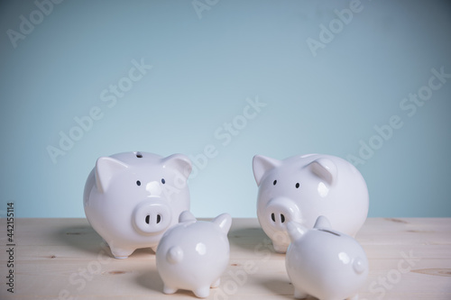 Family white piggy bank on old wood looking at green background. Father and mother little piggyback training save money for growth in the future. Concept family saving money for the future.