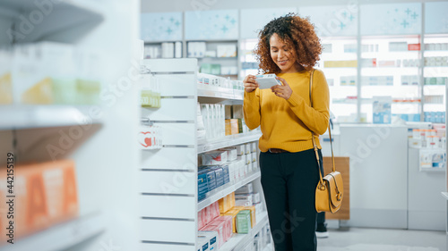 Pharmacy Drugstore: Beautiful Black Young Woman Walking Between Aisles and Shelves Shopping for Medicine, Drugs, Vitamins, Supplements, Health Care Beauty Products with Modern Package Design