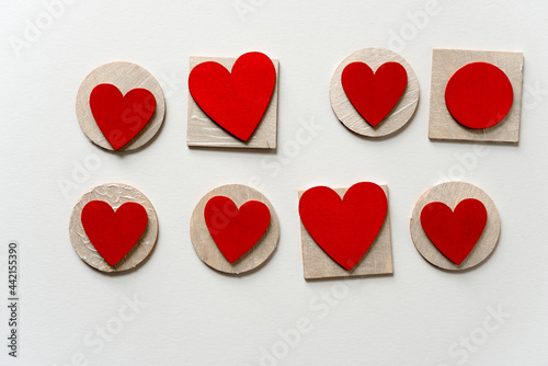 red hearts and circles layered on painted wooden shapes   - loosely arranged on a light background - photographed from above with ambient light