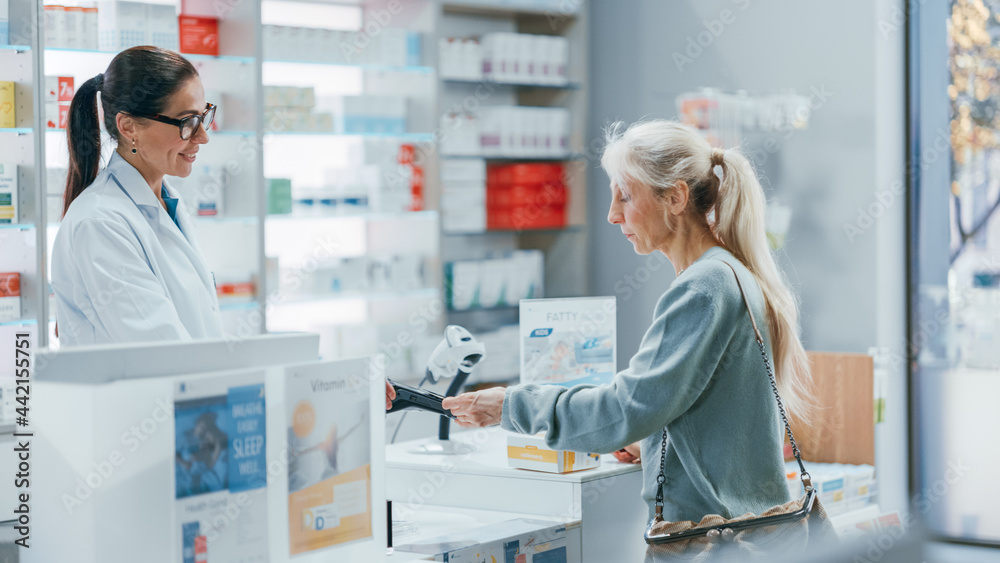 Pharmacy Drugstore Checkout Counter: Professional Female Pharmacist Sells Medicine to Diverse Group of Multi-Ethnic Customers, they Pay Using Contactless Payment Credit Card to Buy Drugs, Vitamins