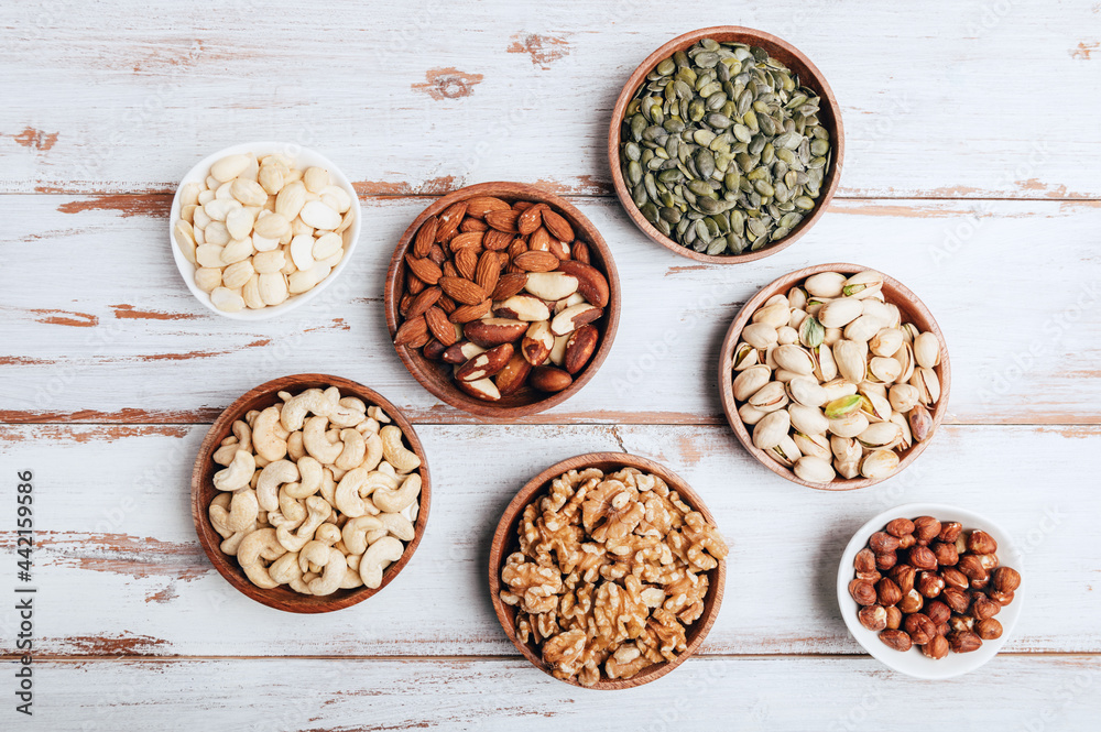 Different kind of nuts in wooden bowls Different kind of nuts in wooden bowls