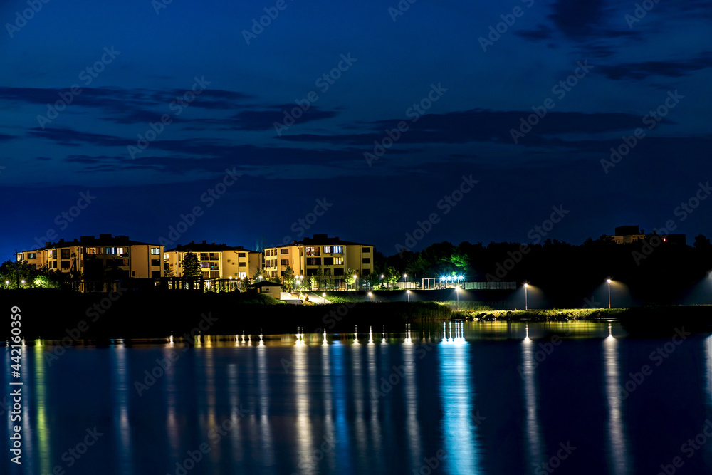 Cottages and villas in the night city with light reflection in the water. Night city on the waterfront.