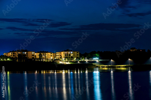 Cottages and villas in the night city with light reflection in the water. Night city on the waterfront.