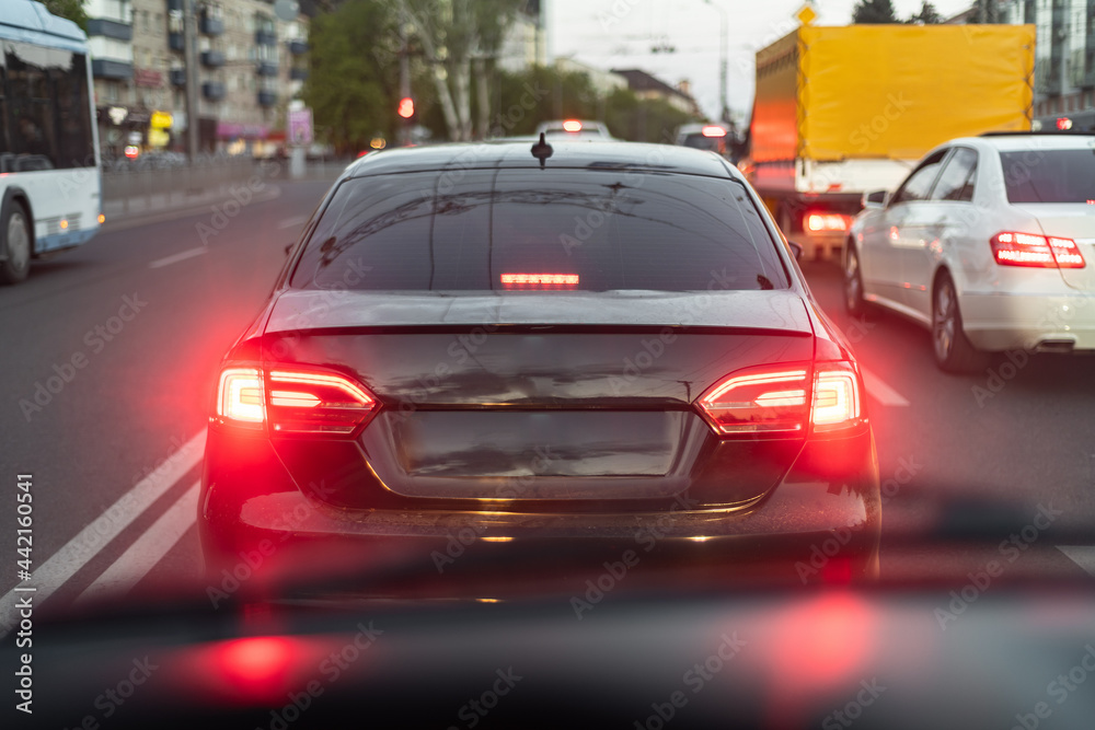 A car in the city stands at a traffic light, waiting for a green light to pass.