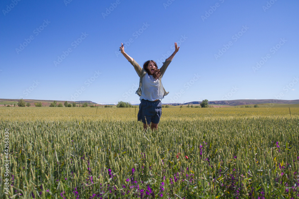 Happy middle-aged woman jumping in the wheat fields. Optimism and enthusiasm Happy middle-aged woman jumping in the wheat fields. Optimism and enthusiasm