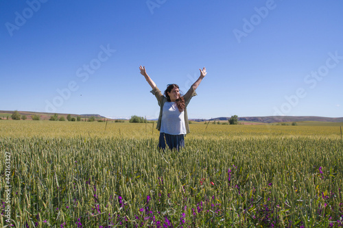 Happy middle-aged woman jumping in the wheat fields. Optimism and enthusiasm