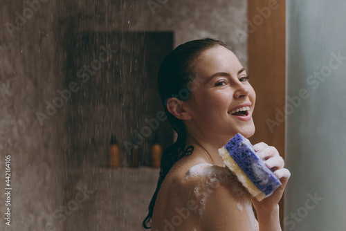 Canvas Print Excited half naked topless young wet haired woman 20s take cold and hot shower use blue washcloth in bathroom do morning routine in brown background