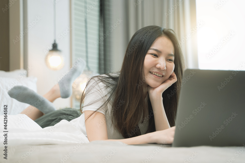 happy Young asian woman working with laptop in bed at home in the morning. lifestyle concept happy Young asian woman working with laptop in bed at home in the morning. lifestyle concept
