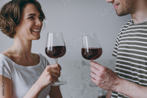 Close up croped up photo shot young smiling couple two woman man 20s in casual t-shirt clothes drink red wine celebrate new dwelling in light kitchen at home together People leisure lifestyle concept.