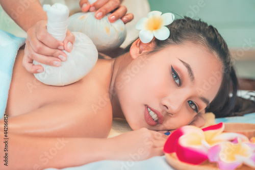 Young Asian woman taking Thai Herbal ball hot compress massage in an authetic spa authentic photo