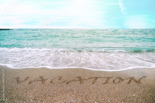 Vacation written in the sand on the beach photo