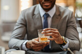 Cropped shot of successful African-American businessman enjoying glass of whiskey in hotel, copy space