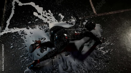 Latex fetish tight rubber suit for bdsm games on woman lying on the floor in white liquid