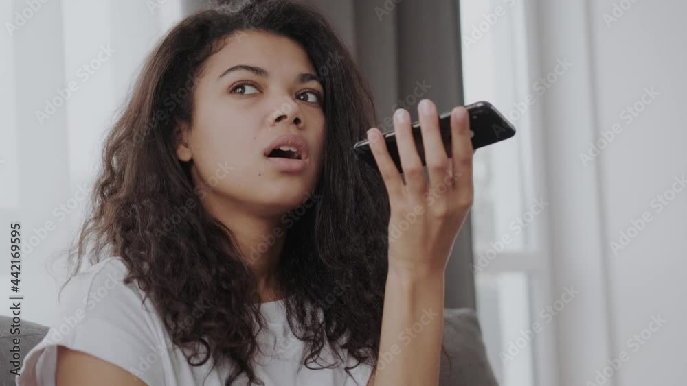Beautiful african American young woman hold smartphone use digital assistant on device, black biracial millennial girl record voice message on cellphone, try new modern gadget app