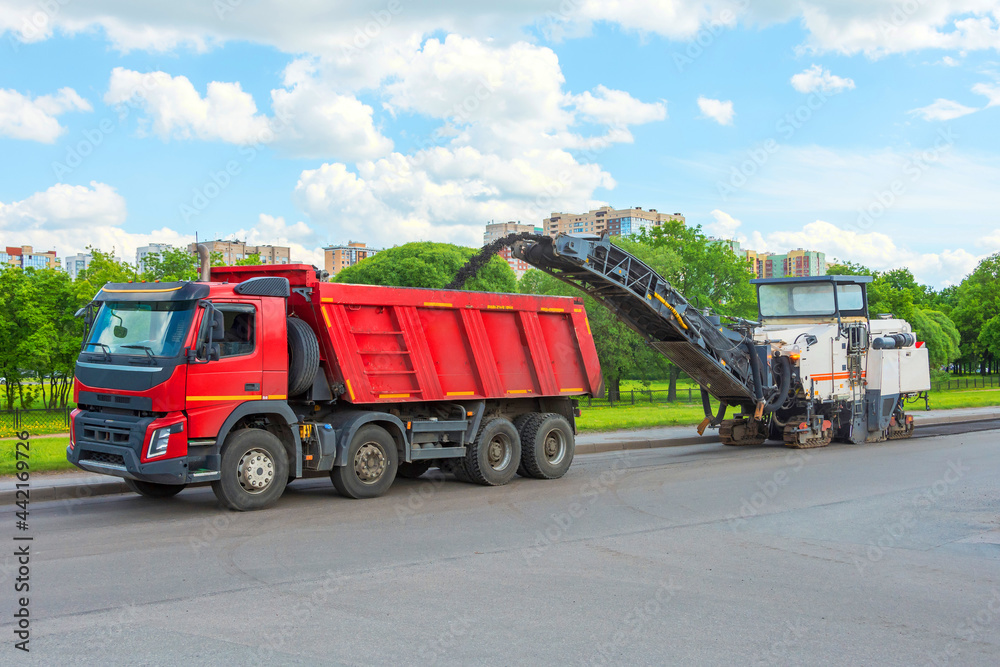 Road cold milling machine removes the old asphalt and loading into a dump truck. Repair of asphalt pavement of the road.