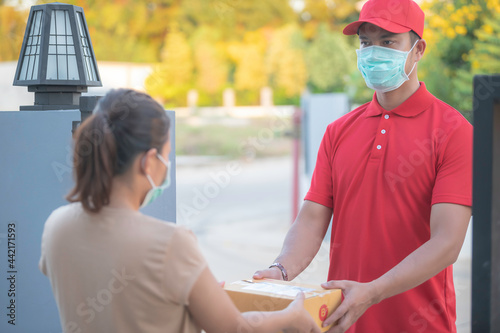 Asian Delivery  man wear protective mask in red uniform,Online food and product delivery concept,New normal in covid-19 © reewungjunerr