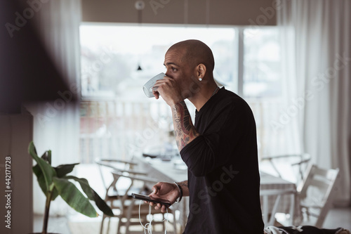 Man står med smartphone i handen och dricker kaffe photo