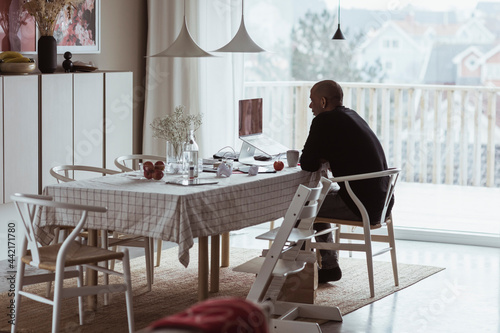 Man sitter vid matbord hemma och pratar med kollega på videomöte photo