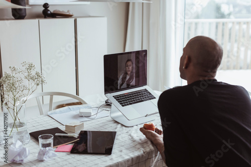 Man pratar med kvinnlig kollega på videomöte photo