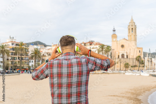 Unrecognizable man listening music with headphones on beach
