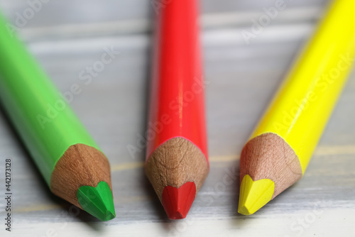 Canvas Print Closeup of isolated colorful yellow, red, green crayons on wood background - tra