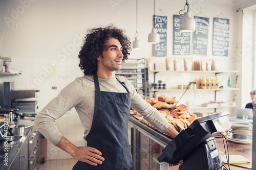 Manlig ägare står bakom kassa på café