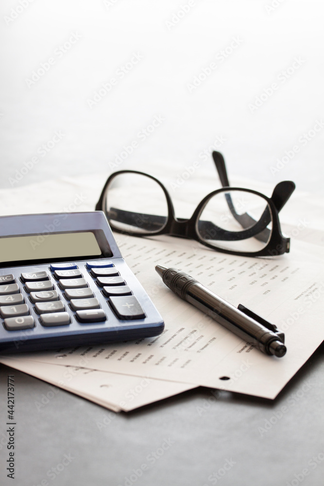 calculator, glasses, pen and papers on white fading background with copy space. Business concept. calculator, glasses, pen and papers on white fading background with copy space. Business concept.