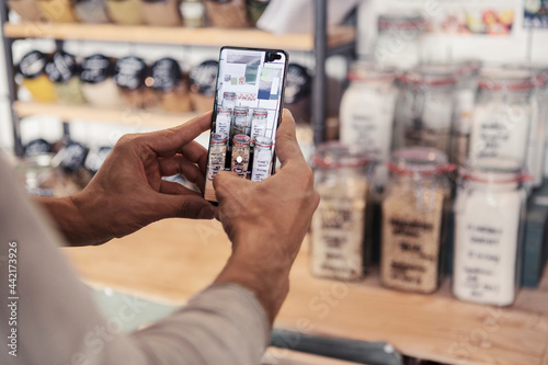 Ägare fotar burkar i butik med smartphone photo