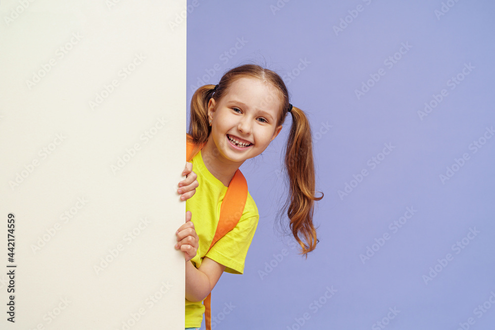happy little preschool girl, without one baby tooth, with two ponytails, looks out from behind the wall copying place for text. joyful, enthusiastic child in bright clothes flaunts. Advertising happy little preschool girl, without one baby tooth, with two ponytails, looks out from behind the wall copying place for text. joyful, enthusiastic child in bright clothes flaunts. Advertising