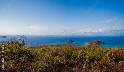 A beautiful panorama from above the tropical island on the blue ocean. We meet a romantic dawn. Clear skies with a thin line of white clouds on the horizon. Two small islands can be seen in the sea.