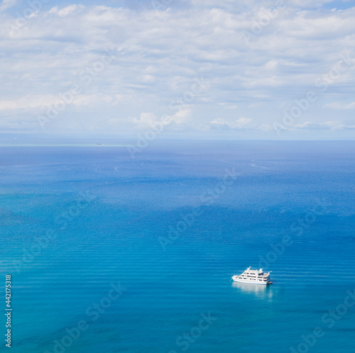 Panorama on the turquoise ocean, blue sky with white clouds and white boat. View from above. Australia. Great Barrier Reef. View from Cook Island. Sunny clear day. Blue background. © Savour_of_day
