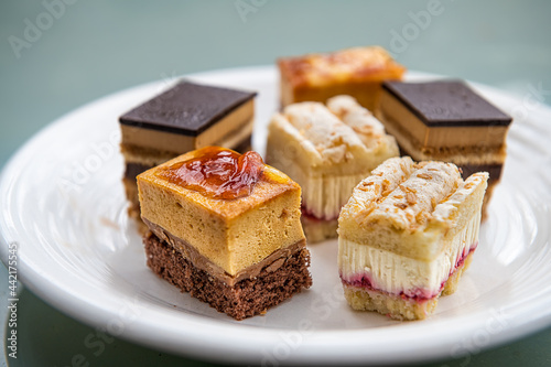 Bite size cake slices closeup with coffee opera, raspberry and chocolate pastry storebought in France handmade