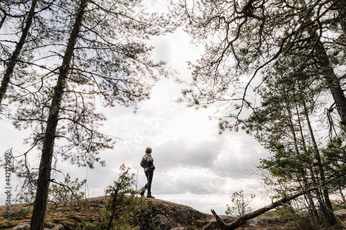 Kvinna går på klippa i skog under molnig dag