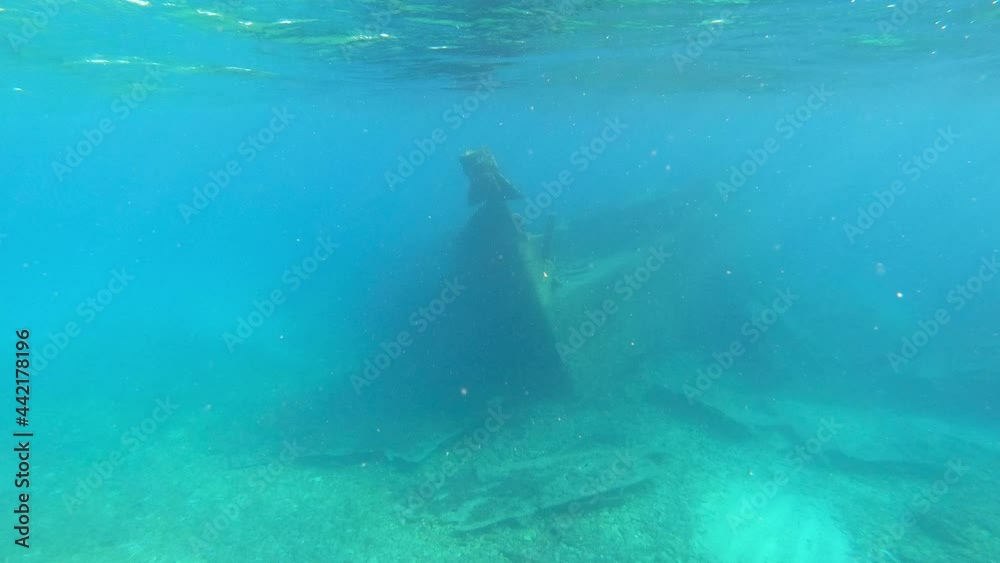 Sunken boat shipwreck on shallow ocean waters. Sun rays and seabed. Shipwreck Michele in Veli Rat, Croatia.